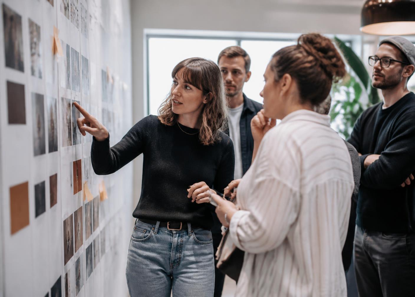 Marketing team reviewing printed campaign layouts pinned to a studio wall